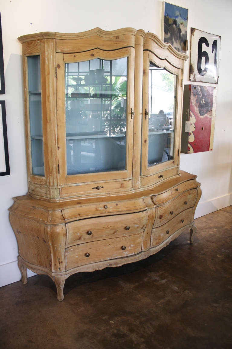 19th century stripped pine cabinet with shapely body of drawers and glass door upper.