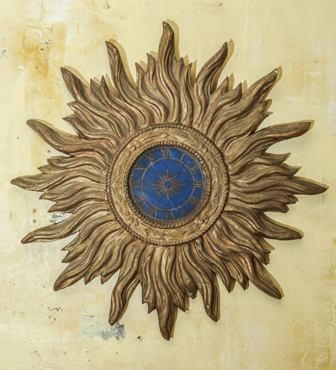 Carved and gilded Italian sunburst with later painted center, late 19th century.