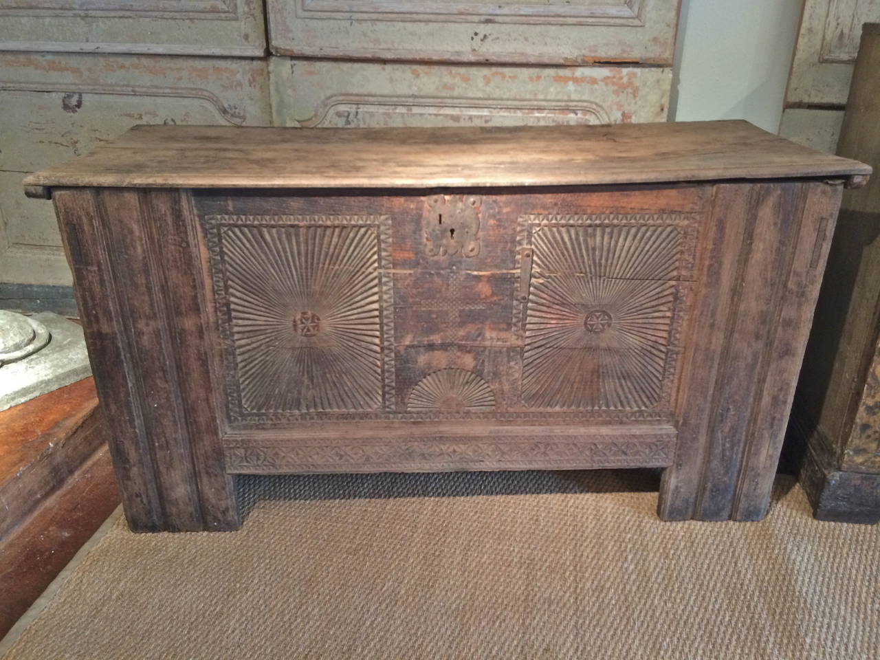 Beautifully carved Spanish chest. Substantial fluted legs run top to bottom. Front panel has crisply carved sunrays on either side with carved cross above sun ray .Original iron lock. Finish is dry.