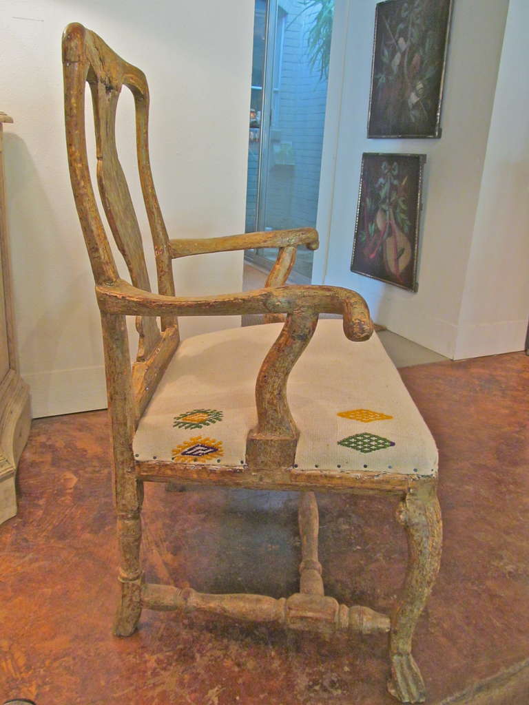 Handsome and vividly carved Rococo arm chair with unsual arms. Scraped to it's original yellow paint.