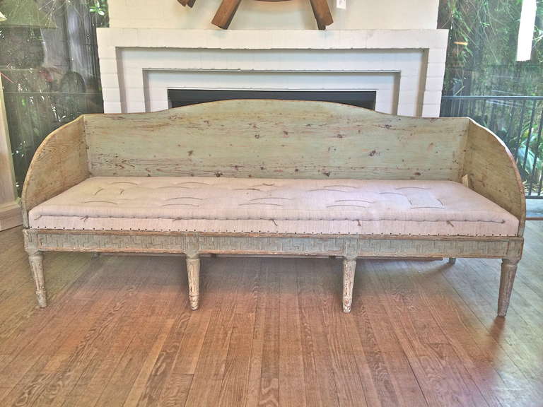 Unusual shaped back and arms on this Swedish Gustavian settee. Modified Greek Key frieze around skirt. Dry-scraped to original blue/green color. Antique linen on tight seat with looses back and arm cushions.