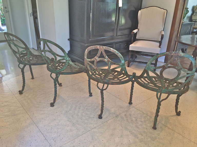 Unusual and beautifully made French Restoration four seat garden bench. Four spoon back and seats supported on triple twisted hand forged legs. Retaining its original surface. Beautifully constructed.