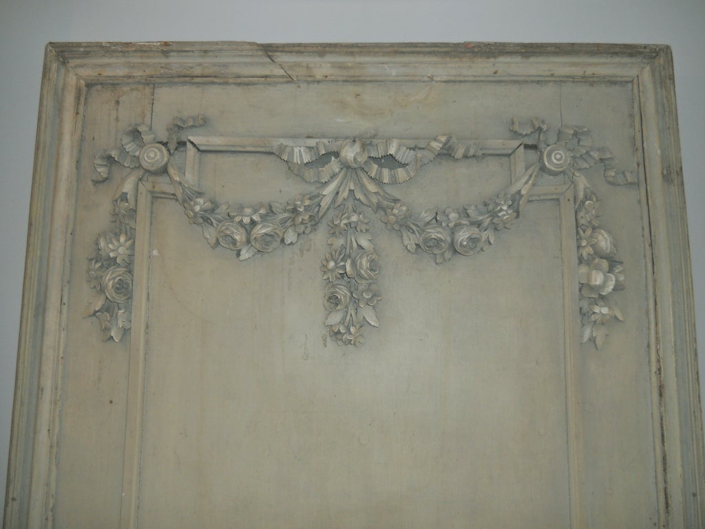 Charming boiserie panel in carved wood depicting an urn with swags of flowers under a ribbon supporting garlands of carved flowers. Paint is a French green.