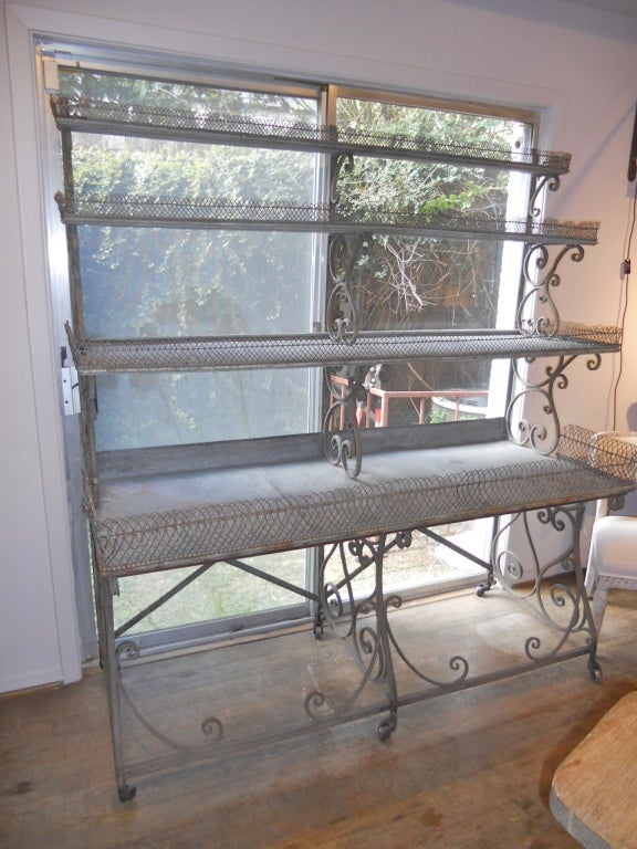 Unusual French 19th. century florists etagere made at Arras ,France. Four zinc shelves , graduated in depth, edged in basket weave wire. Shelf supports in scrolling iron. Original casters.