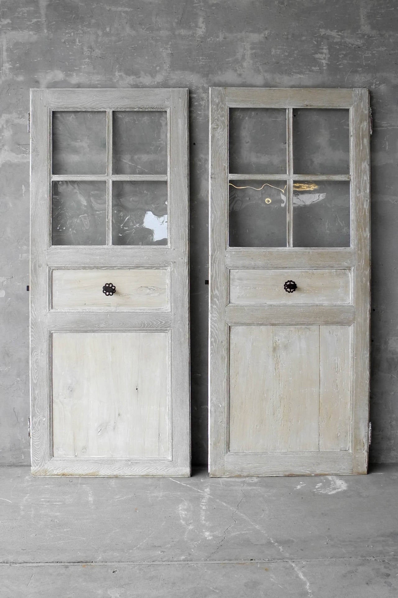 This pair of 18th century antique glass doors originally stood in a Maison de Ville in Perpignan, France. With their delicate blue patina and antique hardware, these doors are a unique find!