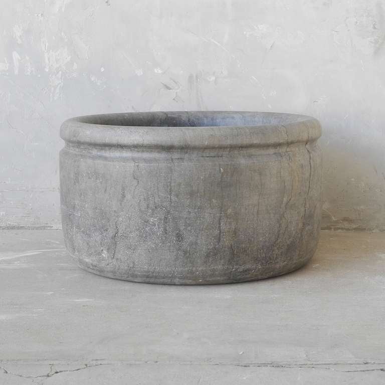 This is a grogeously minimal antique 18th century stone Apothecary Vasque (sink) from the Savoie region of France. It is made of a grey stone and is simply round. It has a carved edge. It can have a hole added to it for easier installation. It would