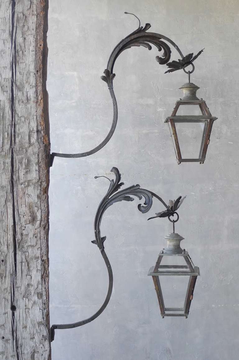This is a pair pf beautifully crafted 18th century lanterns with potence from the Piedmont Region of Italy. The potences are designed to look like greenery, while the lanterns are simple. They boasts a greyish patina and can be electrified if