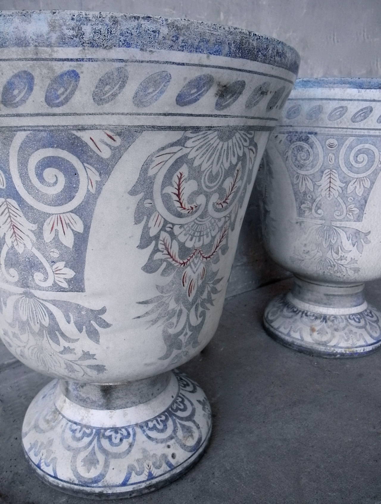 This pair of exquisite 19th century Jarres de Rouen are decorated with a traditional blue and red lambrequin pattern. True to this classic style, these grand vases are enameled cast iron and were signed by their maker, E. Paris & Cie. With their