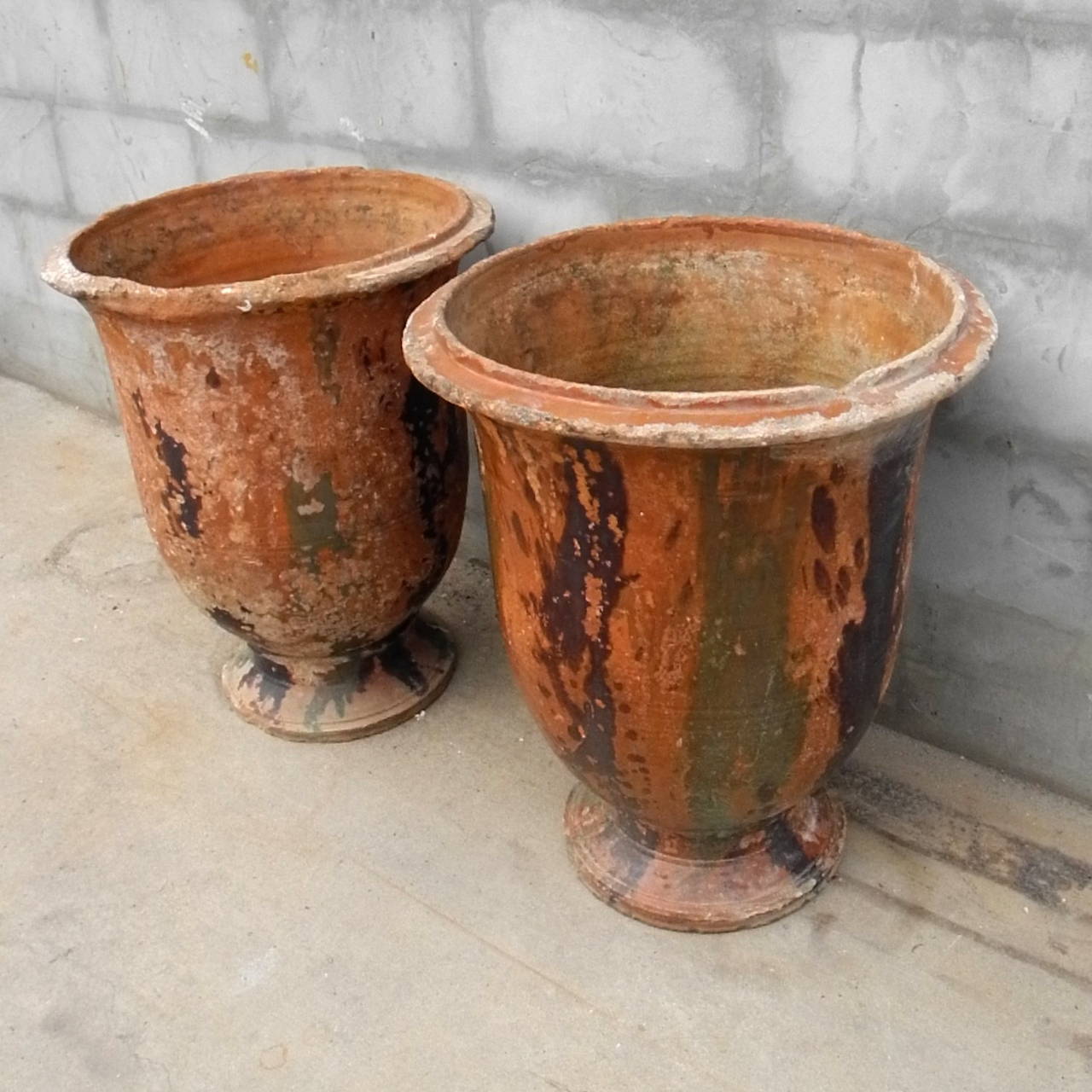 This pair of antique jarres d'anduze originated in France. Their beautiful orange, green, and brown patina makes this a stunning duo. Imagine these items accenting a doorway or flanking a patio.