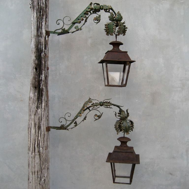 This pair of 18th century Italian potence works well with with a pair of 19th century lanterns.  This fabulous lighting features a floral-like detail on potence., juxtaposed against simple, clean antique lanterns.