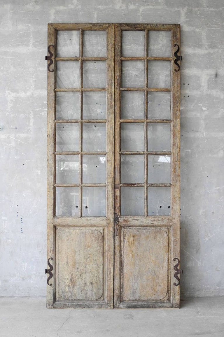 This pair of 18th century French Doors were reclaimed from a Maison Bourgoise in the Isère Region Village of Saint-Marcellin. These walnut doors feature 24 panes of glass and antique hardware. 

At almost 9 feet high, these french doors would make