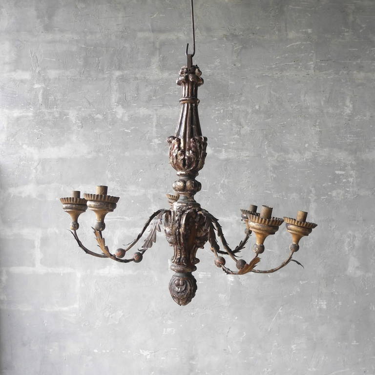 This French antique lustre is circa 1780 and features six arms with a gold-colored leaf design. The base of the chandelier is wood carved with a beautiful pattern. Use this chandelier to add a bit of elegance to any interior space.