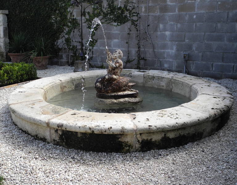 This 18th century reclaimed stone basin with a 19th century iron fountain center of a baby and a swan originally graced a property in Aix-en-Provence, France. It is a good size to center any garden space. Its circular shape give it a very romantic