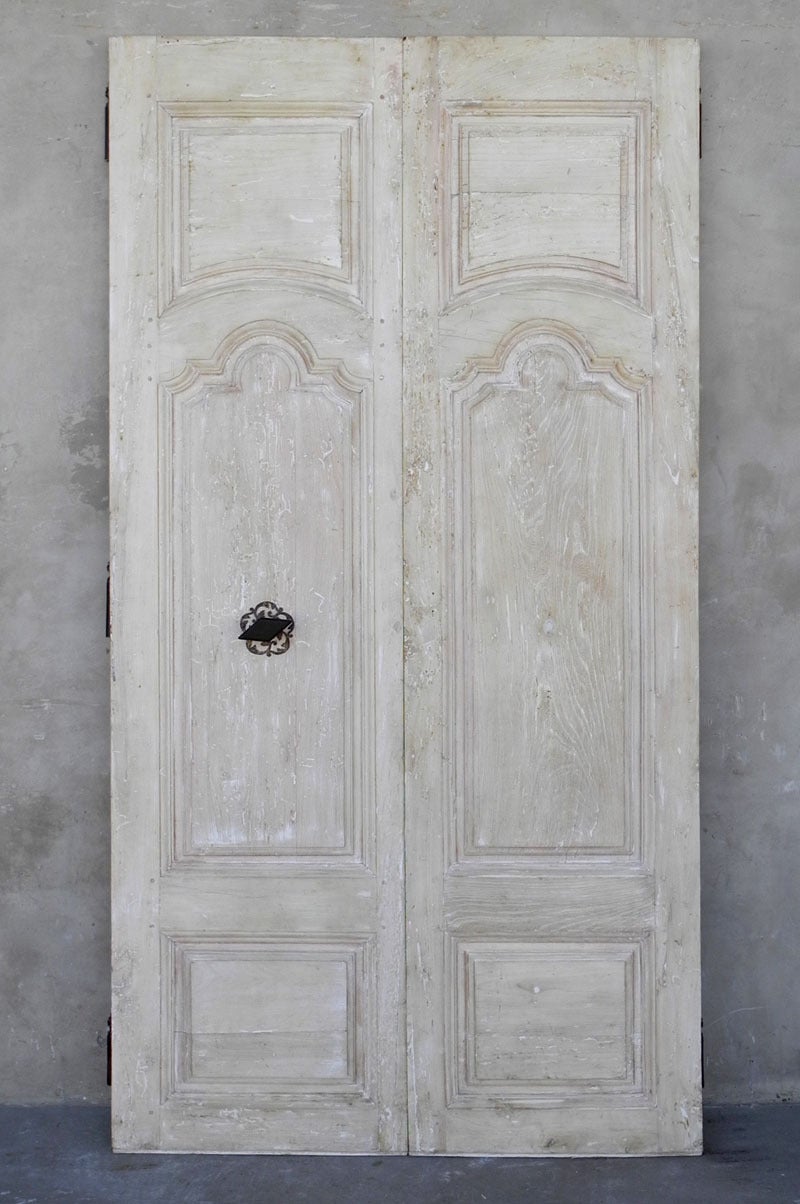 This pair of 18th century walnut entrance doors originally graced the front steps of a Maison de Ville in Uzes, France. These doors feature an antique rosace and knob on the front as well as a locking arm on the back.