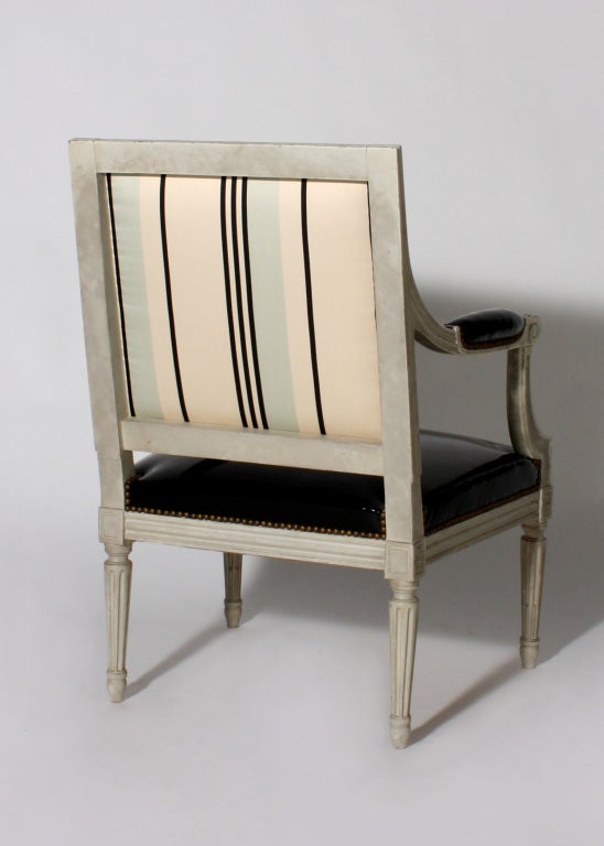 Pair of Louis XVI style fauteuils with black patent leather upholstery and striped back