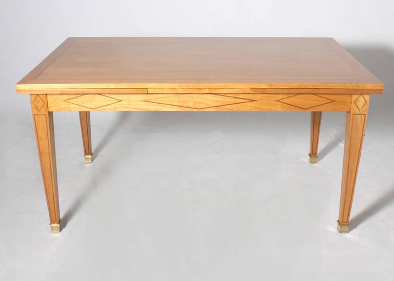 French merisier and brass dining table with parquetry design in the style of Jacques Adnet.Table was refinished in French polish. Beautiful cheerywood with parquetry design on legs and base. 
Table and chairs can be sold individually or separately.