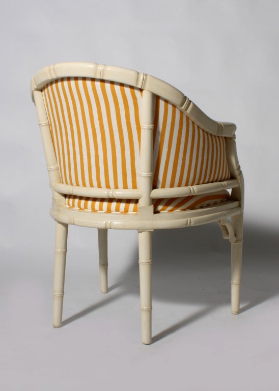 Pair of faux bamboo barrel chairs in antique French ivory with yellow and ivory striped upholstery
