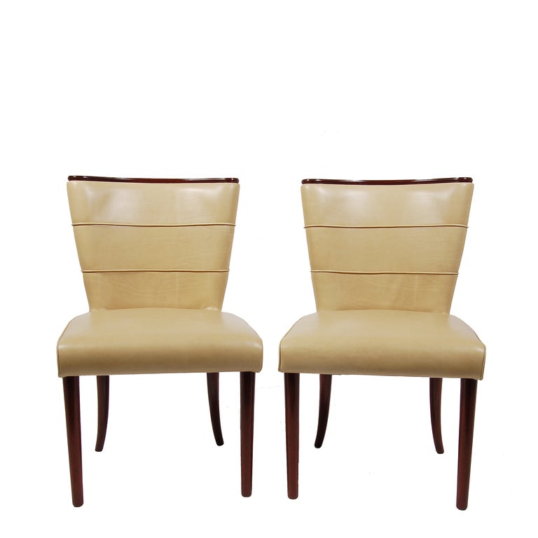 Pair of curved back chairs upholstered in new leather with solid mahogany top trim and legs, spring construction in seat.