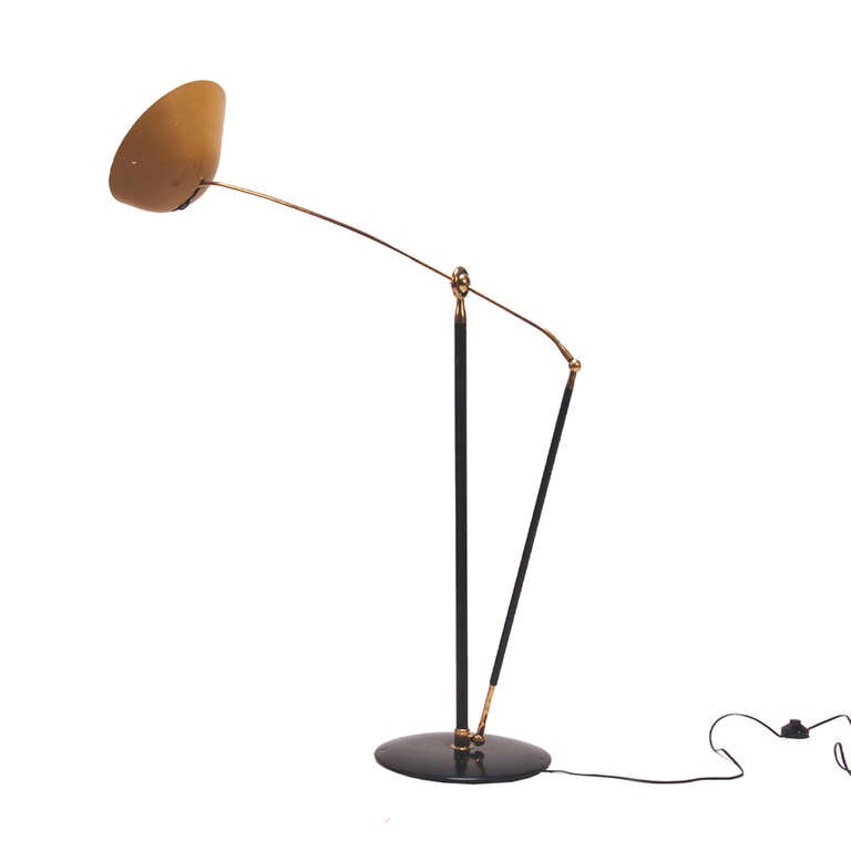 Extremely rare floor lamp by the founder of the Italian lighting company, Arredoluce. Height adjustable, adjustable shade and swivelling on round balance ball. Enameled metal shade on black painted metal frame with brass detail.
Marked on