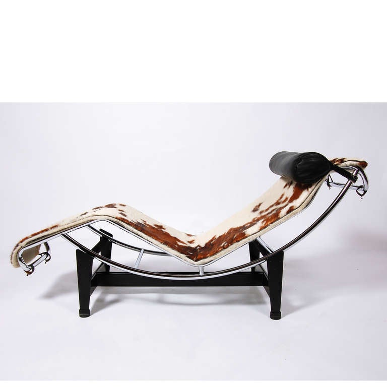 Classic adjustable lounge with cowhide pad and black leather head pillow on curved polished chrome frame, sitting on black painted metal base. Signed in frame. Designed in 1928, this piece made approximately 1970's.