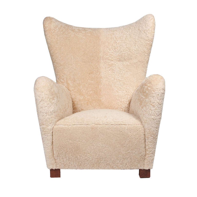 Freeform high back wing chair with large curved arms, on mahogany stained beech legs.
Reupholstered in sheepskin. Made by Fritz Hansen, in 1942 catalog, page 12.