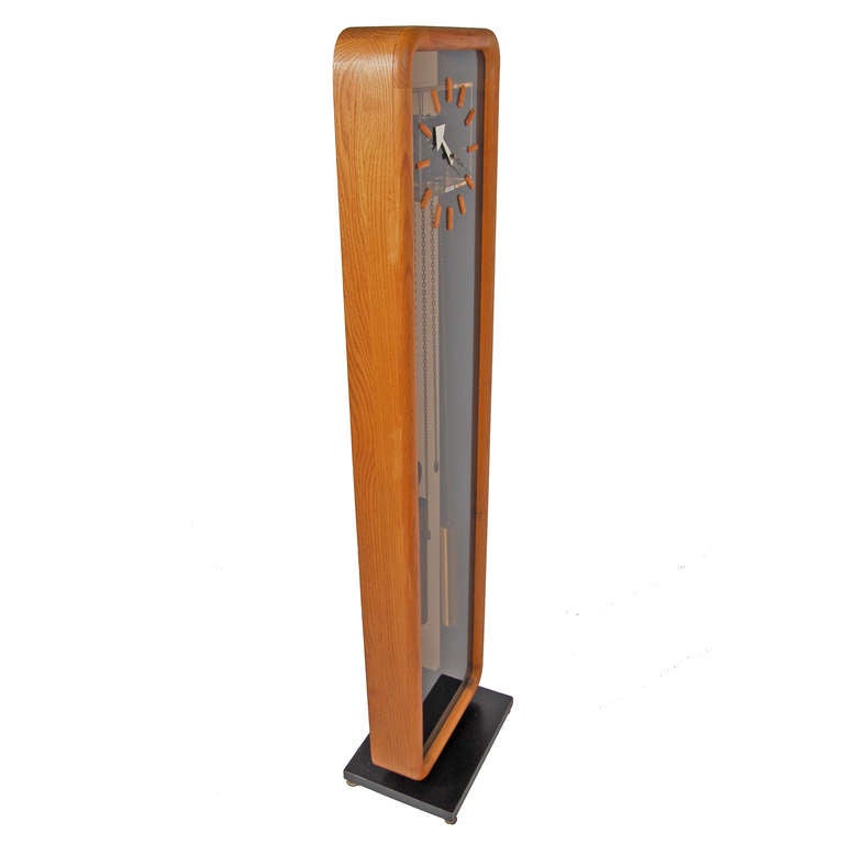 Floor clock, model number 622. Solid oak case concealing lucite front  and cover for works. Brass weights and pendulum. Chimes at quarter hour and hour. Iconic clock face.
