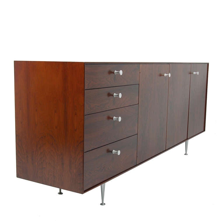 Rosewood credenza with four drawers and three doors opening to reveal adjustable shelves and open storage space. Aluminum tapering legs. Retains label. Made by Herman Miller.