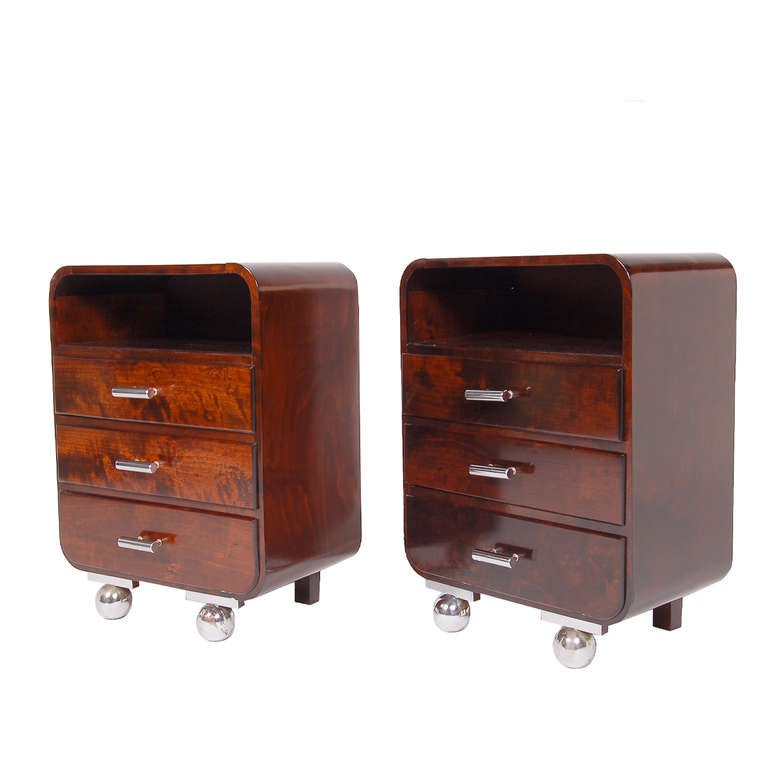 Two small nightstands with three drawers and one open space. Chrome pulls and chrome ball feet in front. Mahogany stained plywood case and drawers.