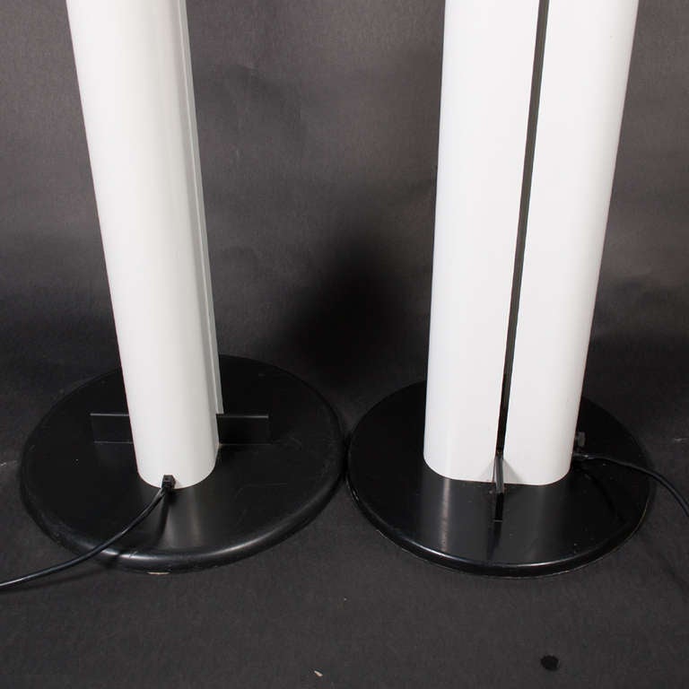 Tall floor lamps, anodized aluminum column, base of steel covered with thermoplastic synthetic resin.  Sliding side dimmers. Halogen lights.
Gloss white.  Made by Artemide.