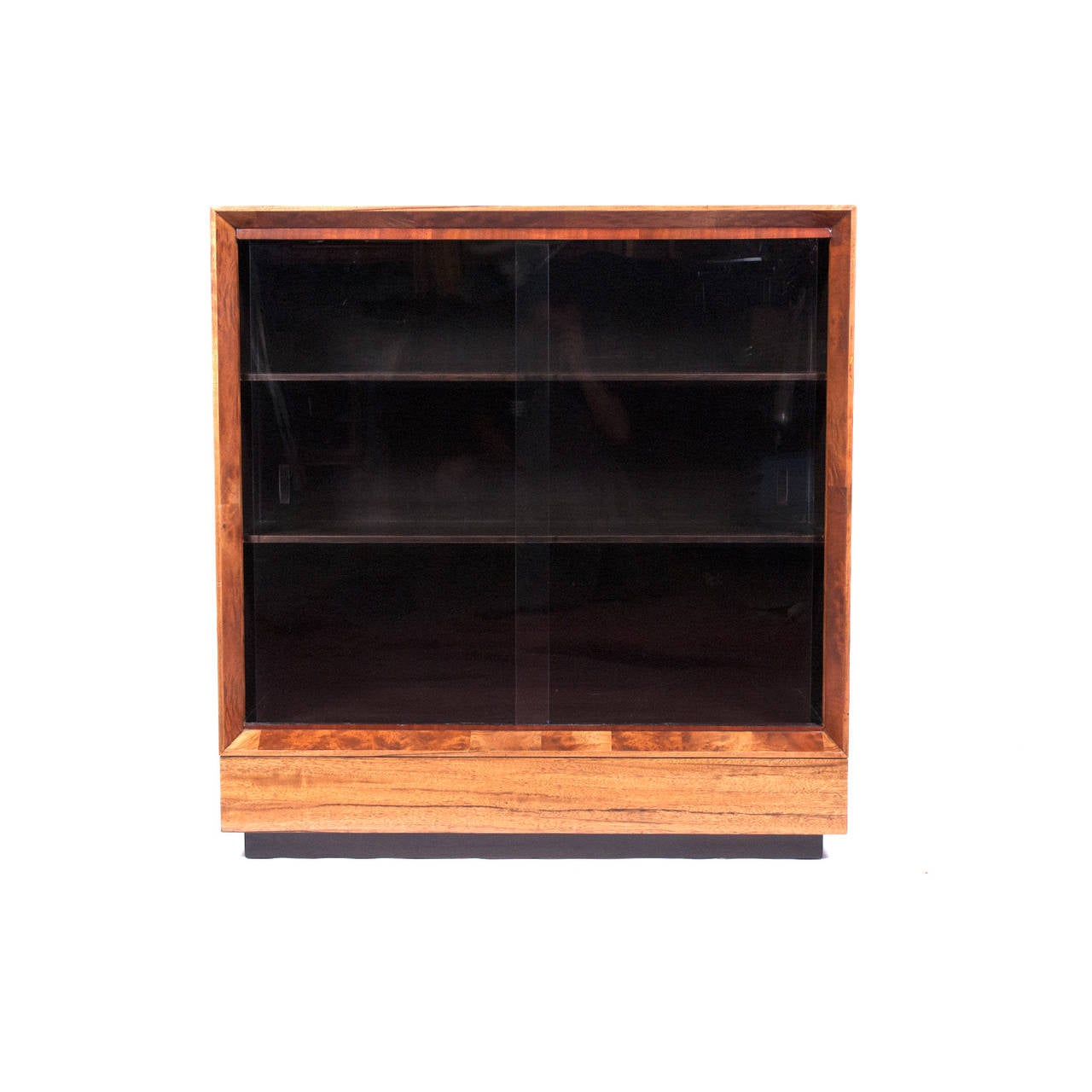 Bookcase in exotic paldao wood with two sliding glass doors and two interior shelves. Restored. Made by Herman Miller.