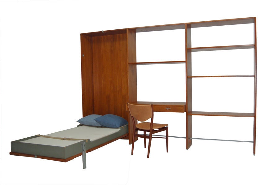 Unusual wall unit, RY 100, with drop down single bed. Front of bed panel is cane, finished on the back for use as a room divider. It also has four shelves and a desk with two drawers, all height adjustable. Teak with metal support rods. Made by RY