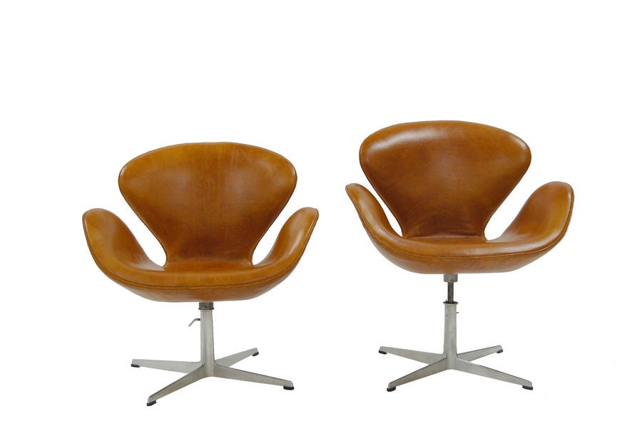 Rare version of the Swan chairs; height can be adjusted from lounge to dining height. New leather upholstery on original aluminum swiveling frames. Made by Fritz Hansen.