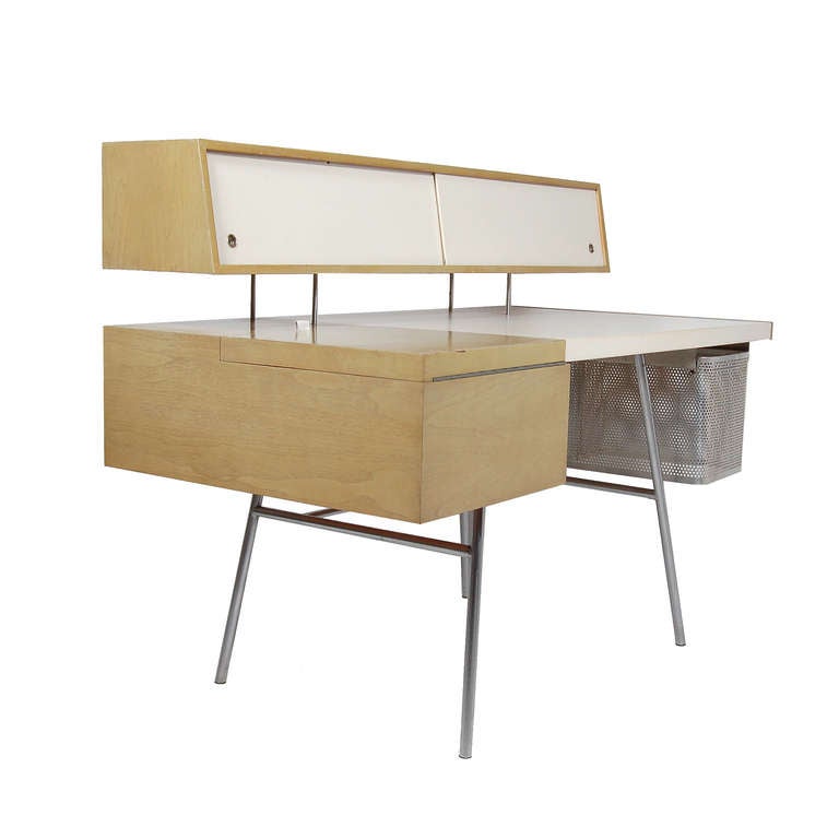 Nelson's early home desk, model 4658, custom ordered in bleached walnut with white leather top and sliding doors. 
Drop down panel and sliding upper doors reveal drawers and small niches. Retains perforated Pendaflex file basket. All on steel base.