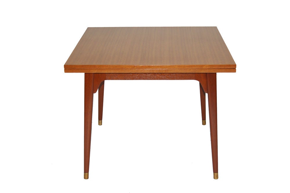 Flip top table, mahogany top on solid mahogany legs with brass feet. Top pivots and unfolds. Extends to 68
