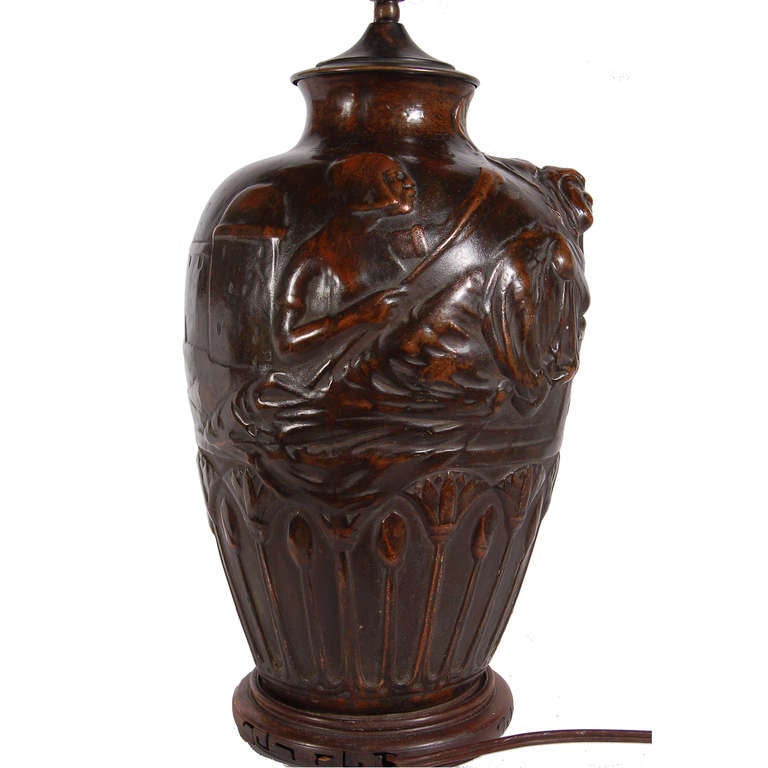 Table lamp made of copper over ceramic, with raised Egyptian motif.
Illegible signature. To front; circular stamp on base.
No shade; height of base without socket 13.25
