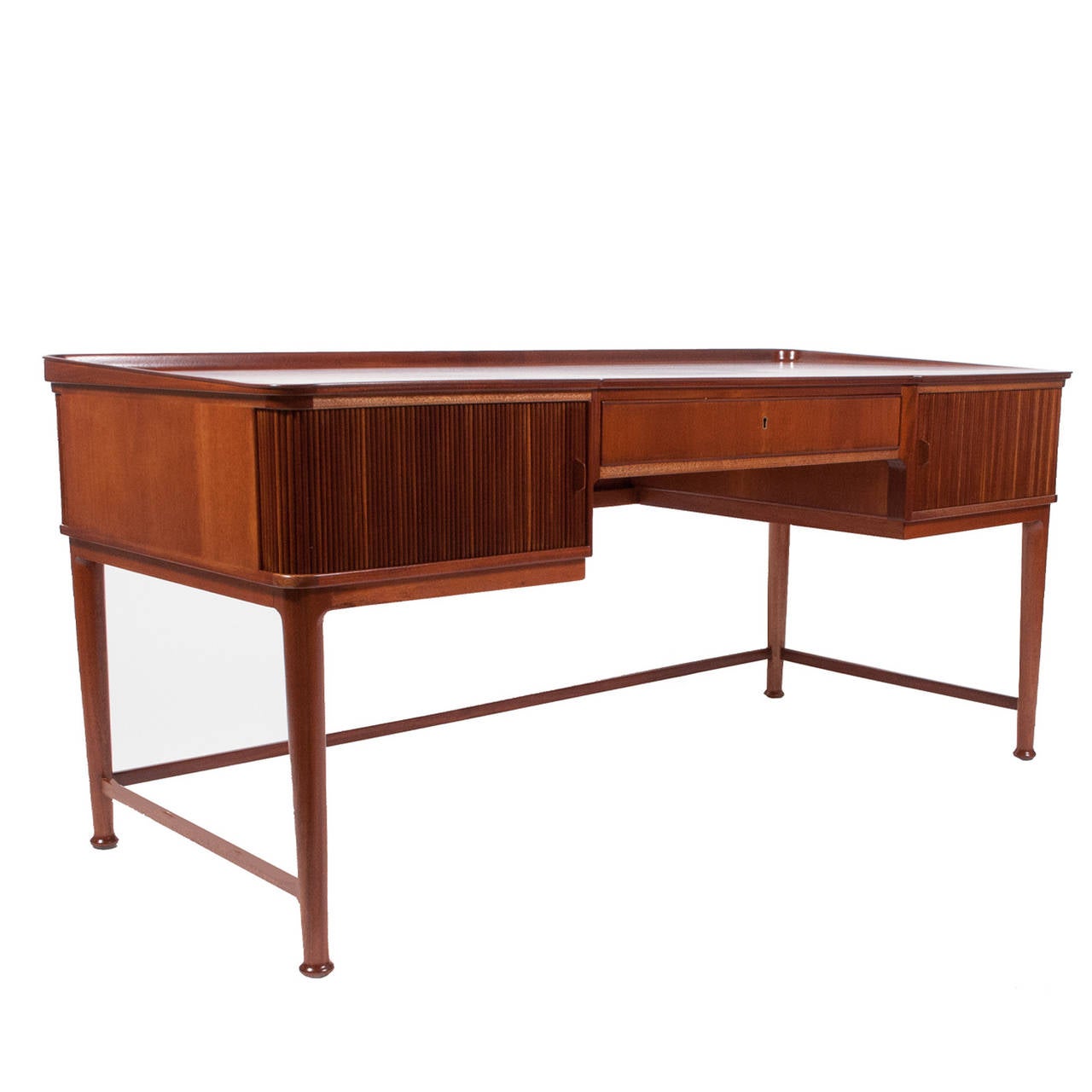 Beautiful mahogany desk with birch interior; tambour doors on each side revealing two drawers each. Top with lip; back of desk also with tambour doors revealing shelves. Solid mahogany legs and stretchers. Made for Svenskt Tenn.
