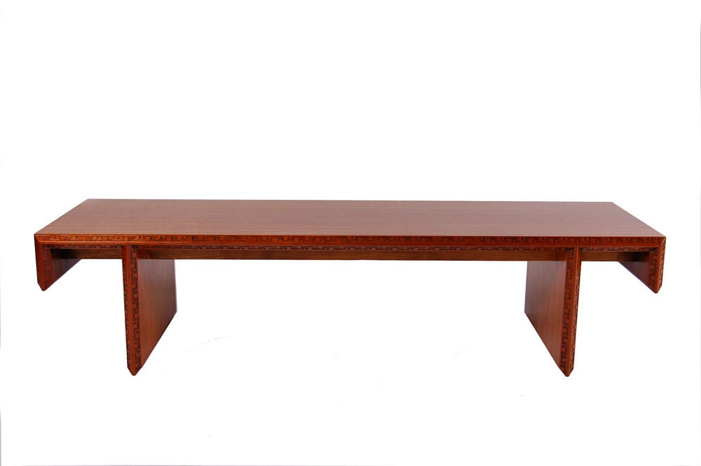 Long coffee table in mahogany with Taliesen design edge; on plank base.<br />
Signed with FLW and manufacturer's mark.  Made by Heritage Henredon.