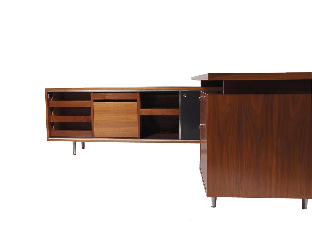 Beautiful L-shaped executive desk, walnut with cane modesty panel. Credenza has sliding Masonite doors which reveal drawers, file drawer and pull out shelf with extension cord. Work surface with drawer and locking file drawer. Work surface measures