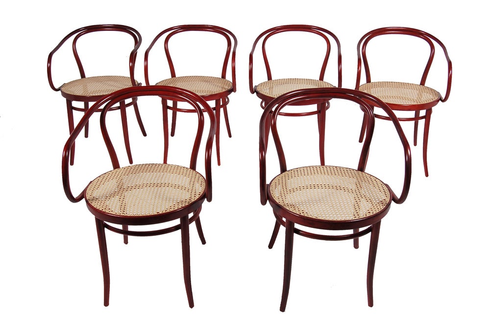 Set of six bentwood armchairs, originally designed in 1902-3. Low back and curving arms with hole by hole cane seat, these chairs were used by Le Corbusier in his Pavillon de l'Esprit Nouveau building. Red stained beechwood. Made by Thonet and