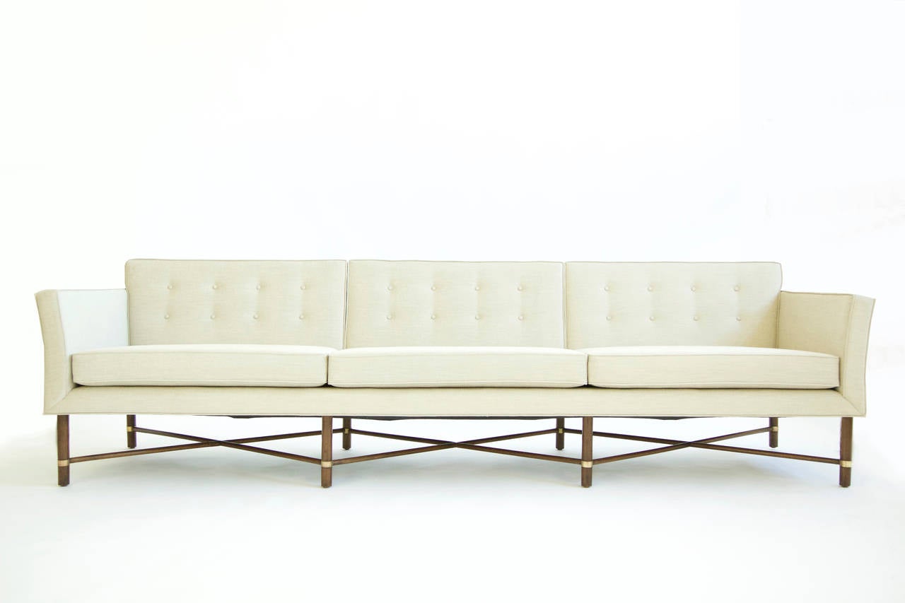 Probber design, rare sofa with criss cross stretchers, brass collars on vertical solid walnut legs, also features slight curved arms with two bolsters.
Reupholstered with great plains fabric.