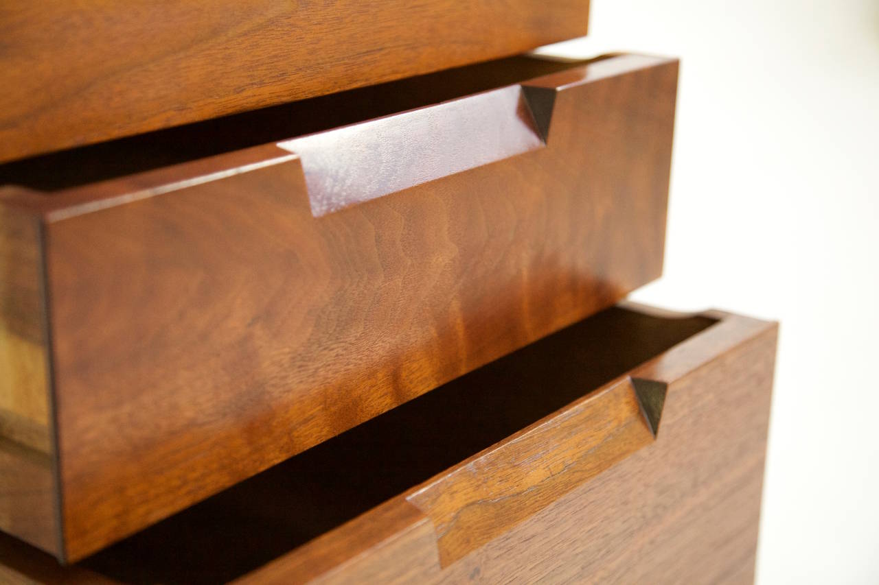 Nakashima Studio nightstand or end tables, three-drawer cases with cut-out recessed pulls in American black walnut.