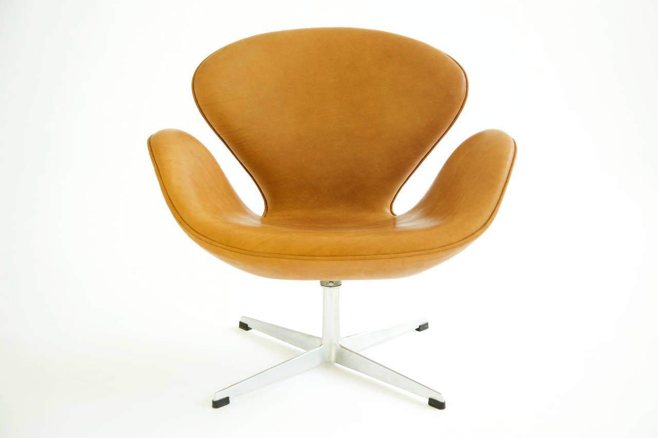 Jacobsen for Fritz Hansen, swivel Swan chairs, hand-stitched leather with cast aluminum base, chrome-plated steel stem, plastic glides- Decal manufacturer’s foil label- [FH Made in Denmark by Fritz Hansen].