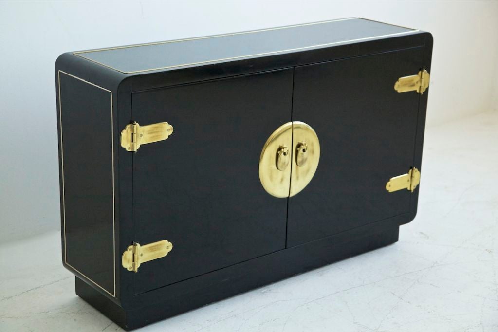 Pair of black lacquered cases, features inlaid brass edge details on sides and top, stylized brass hinges and medallion plate with hanging pulls. Single adjustable shelf.