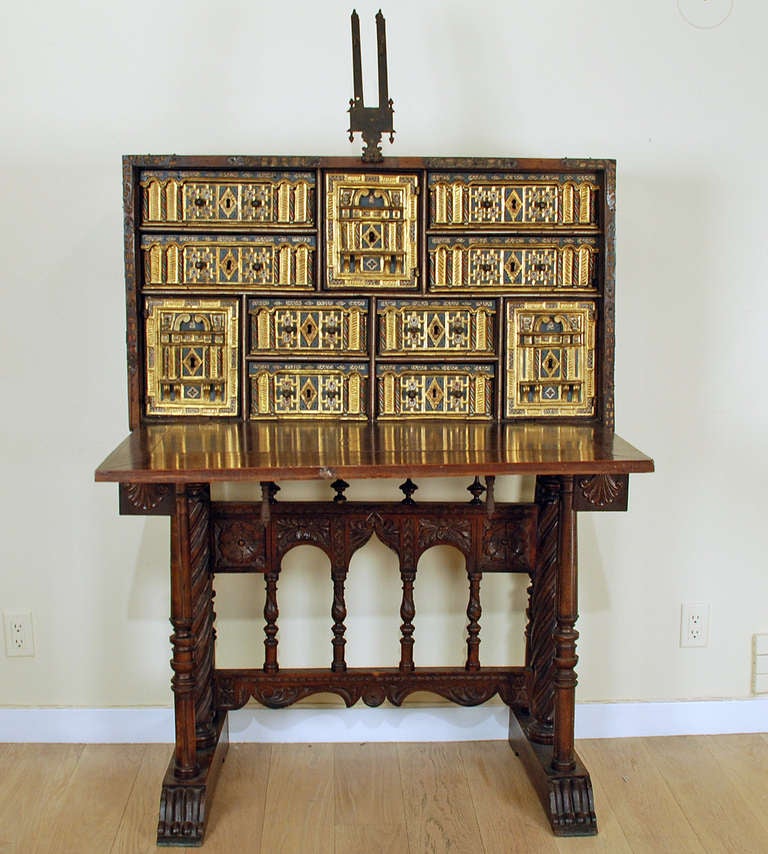 A stunning late 16th century Spanish fall front vargueño with elaborate iron hardware mounted over fine English silk. The interior with eight gilt-wood compartments and three doors, all with elaborate carving, ornate detail and original iron drawer