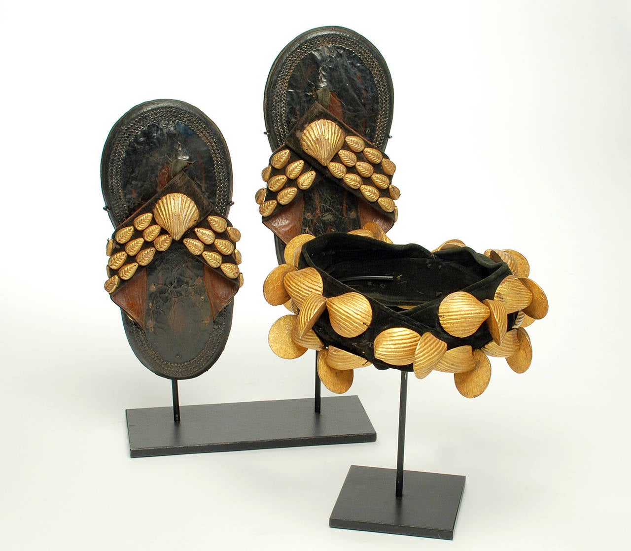A very rare early 20th century Ashanti royal crown together with matching royal sandals, both worn by village kings, Ghana, circa 1930-1940s. The crown with hand-carved and giltwood clamshells. The leather sandals also with giltwood clamshells. Rich