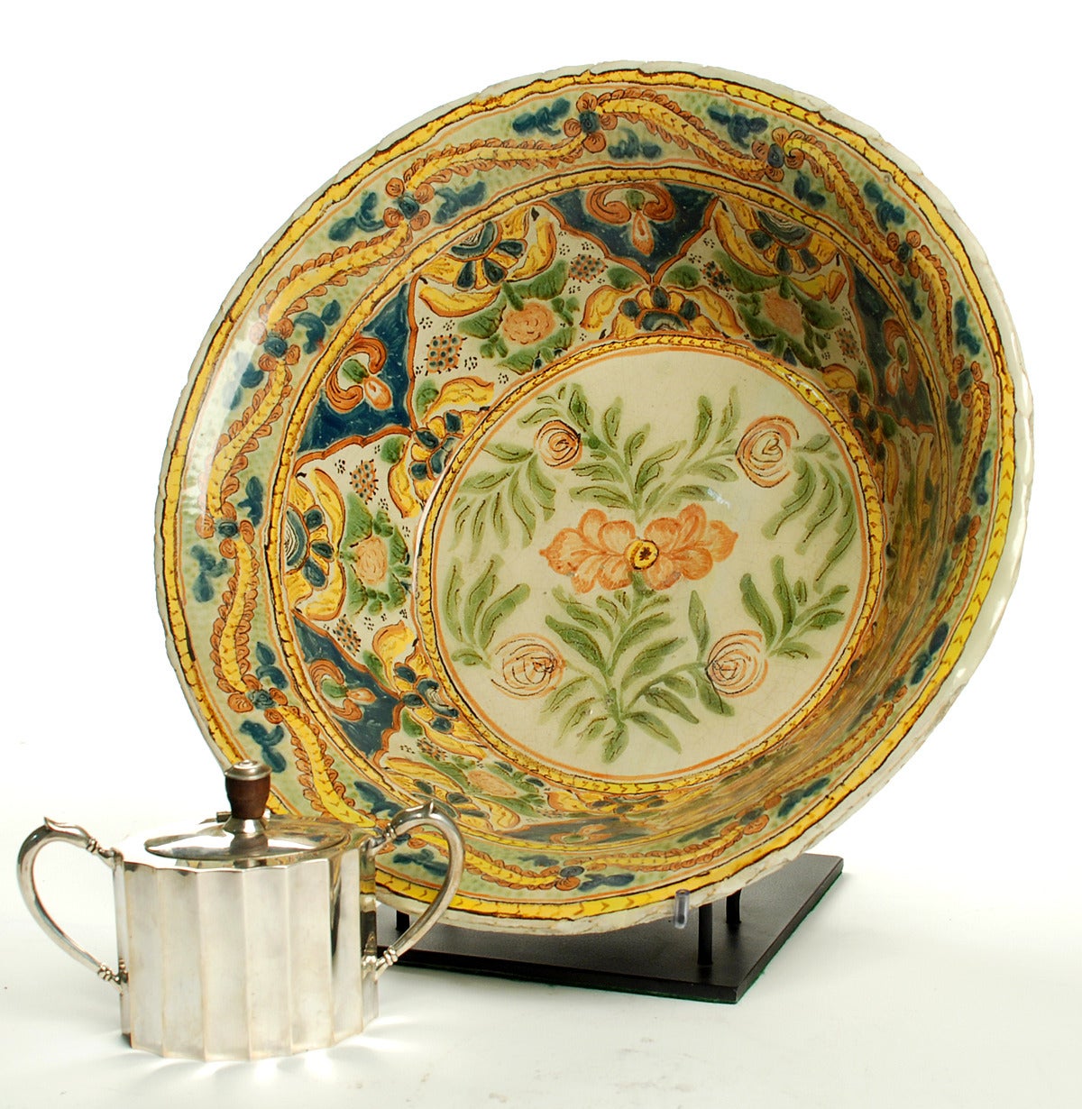 A superb late 18th-early 19th century talavera Poblana Majolica lebrillo with colorful floral motif in olive green, copper green and salmon surrounded by rings of yellow / gold and cobalt foliate patterns. Puebla, Mexico, circa 1800. 

Displayed