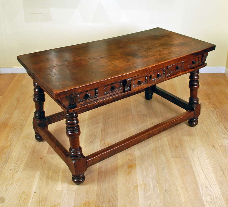 A superb late 17th century Spanish baroque center table with a solid walnut top over a paneled apron with three drawers on each side. The legs, turned and slightly splayed, all joined by a perimeter stretcher. With a warm and lustrous surface