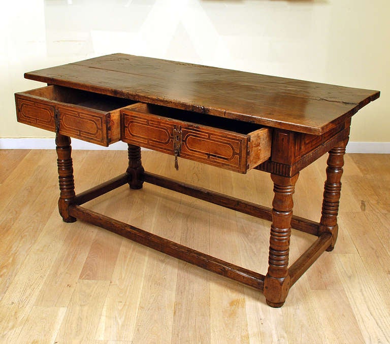 A superb 18th century Spanish baroque period walnut center table with a solid walnut table over two fruitwood inlaid drawers and turned legs connected by a perimeter stretcher base. Continuous fruitwood inlay on all four sides. 

Dimensions: 64