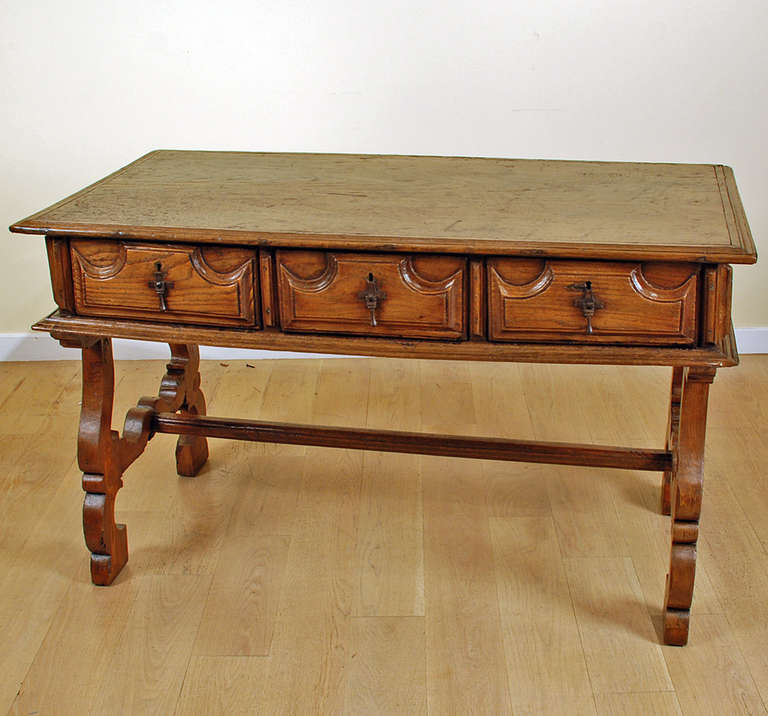 A fine late 17th / early 18th century Spanish baroque period chestnut desk with a single plank top over three heavily carved drawers and lyre legs connected by a stretcher base. In overall excellent condition with lustrous surface patina.