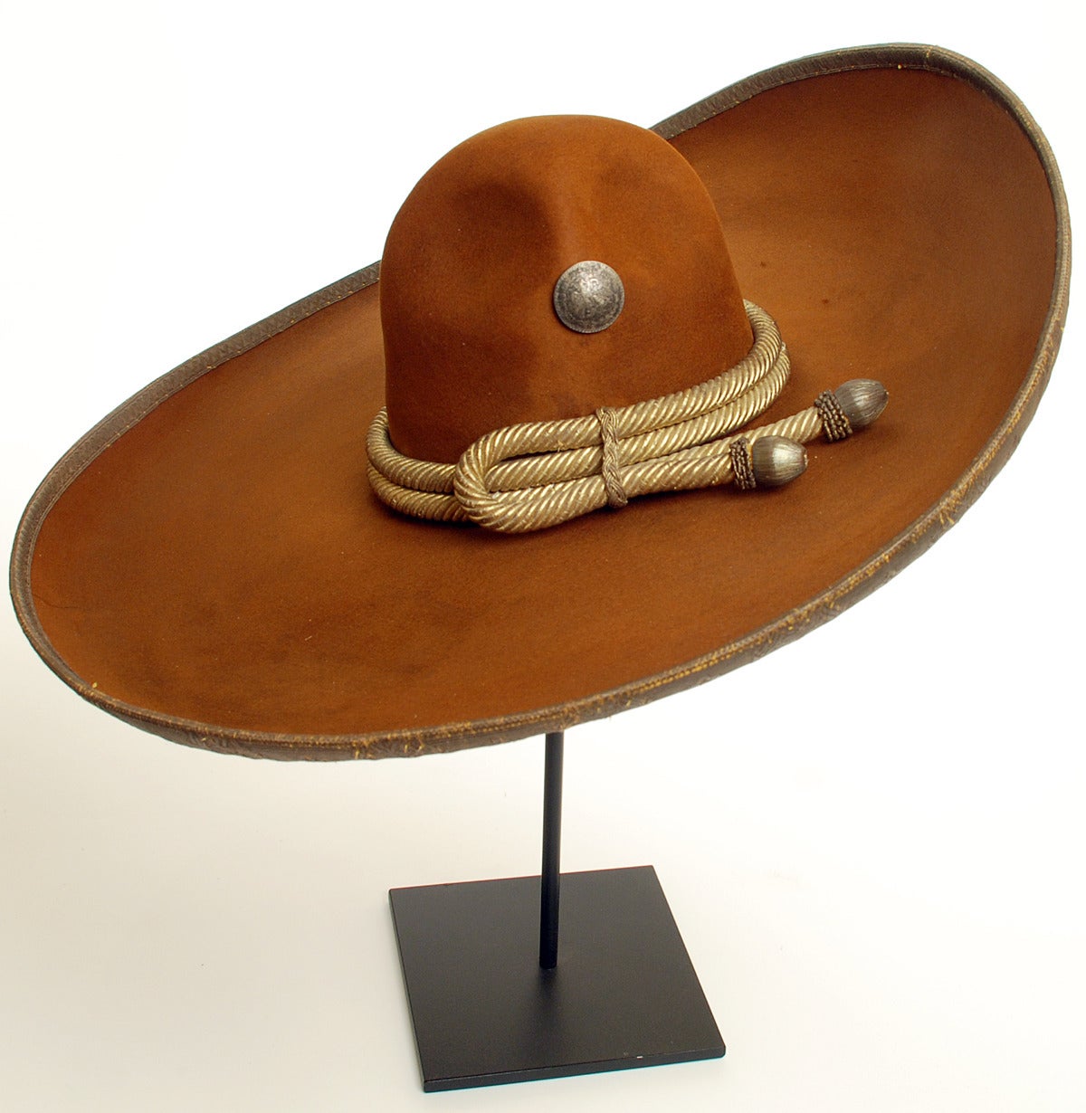 A handsome early 20th century Mexican felt sombrero with original gold threaded fiber cord, silver threaded tassels, and metallic threaded trim - studded with early Mexican silver conchos. Circa 1920. Displayed on a high quality custom made stand.